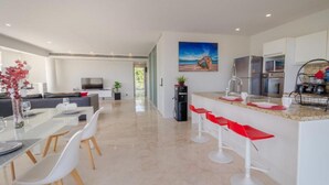 A modern kitchen with a marble countertop, a built-in oven, and a stainless steel refrigerator. - Magia by Zamá Homes (Playa del Carmen)