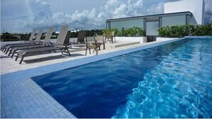 Uma área de piscina moderna com espreguiçadeiras e um edifício com paredes de vidro.