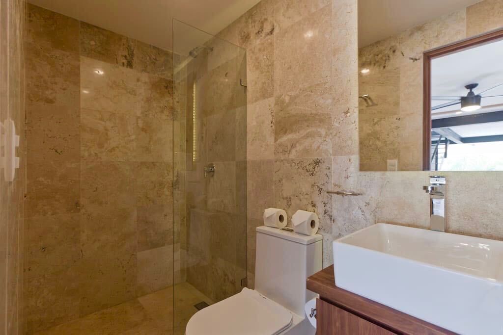 A modern bathroom with a glass-enclosed shower, a white toilet, and a large bathtub.