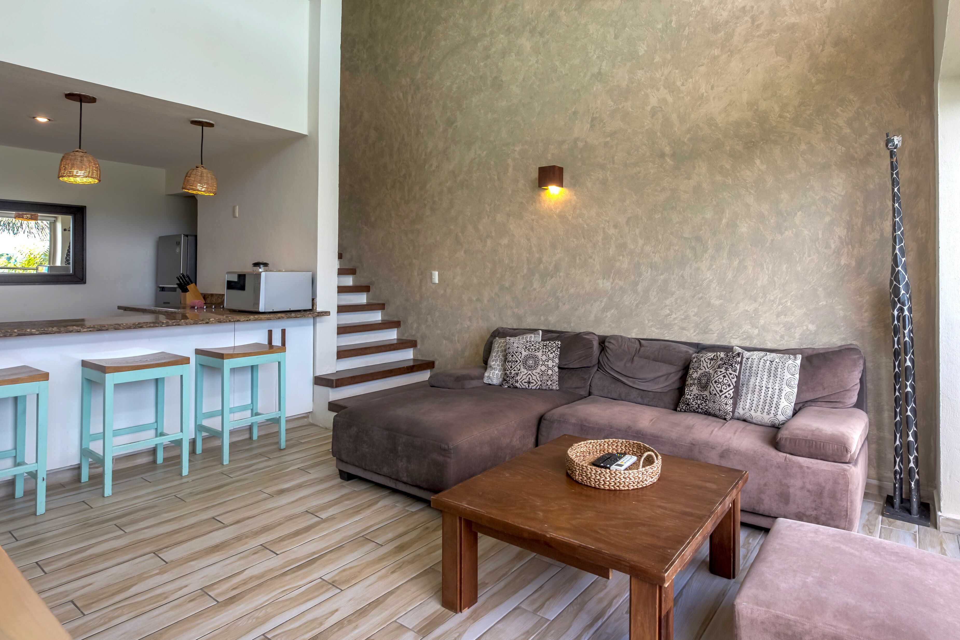 Una sala de estar moderna con un sofá marrón, taburetes de color aguamarina y una mesa de centro de madera.
