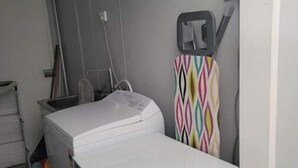 Ein Waschbereich mit Waschmaschine und Trockner, einem Wäscheständer und einer Tür, an der ein Handtuch hängt.