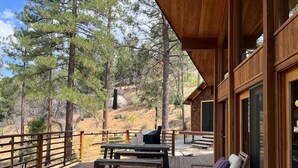A wooden deck with outdoor seating, a grill, and a view of a forested hillside. - 4 Acre A-Frame Private Retreat (Idyllwild)