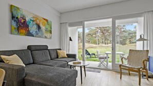 Ein modernes Wohnzimmer mit einem grauen Sofa, einem runden Couchtisch und einem Gemälde an der Wand.