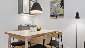 Ein stilvoller Essbereich mit Holztisch, schwarzen Stühlen, einer schwarzen Pendelleuchte und einem Bild an der Wand.