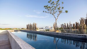 Una piscina con estructuras de madera y un árbol al fondo.