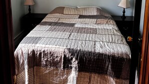 A bedroom with a bed, two bedside lamps, a ceiling fan, and an air conditioning unit. - Cozy 2-bedroom cabin between Levering and Cheboygan on Lancaster Lake (Levering)