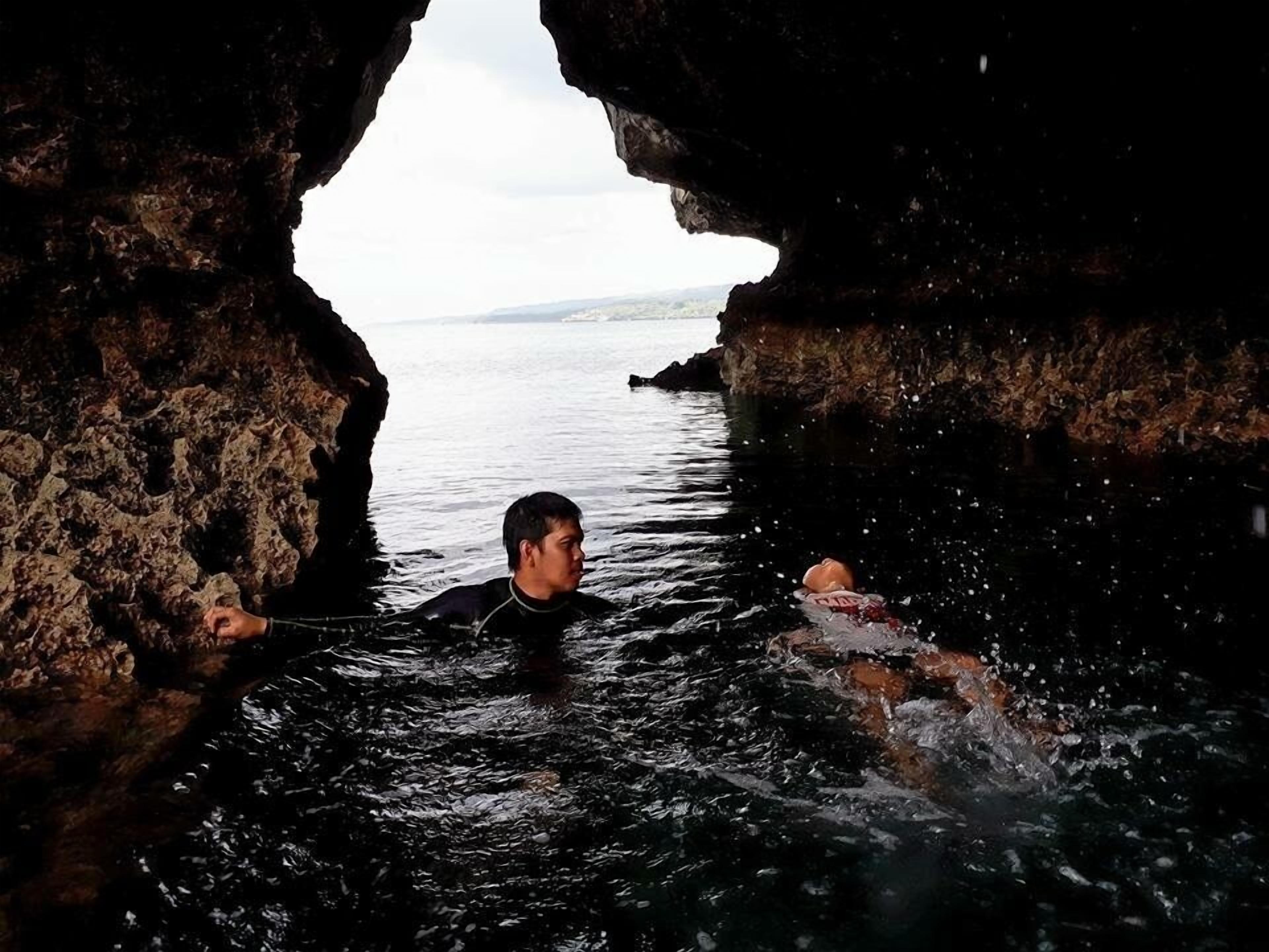 A person swimming in a cave with a view of the sea.