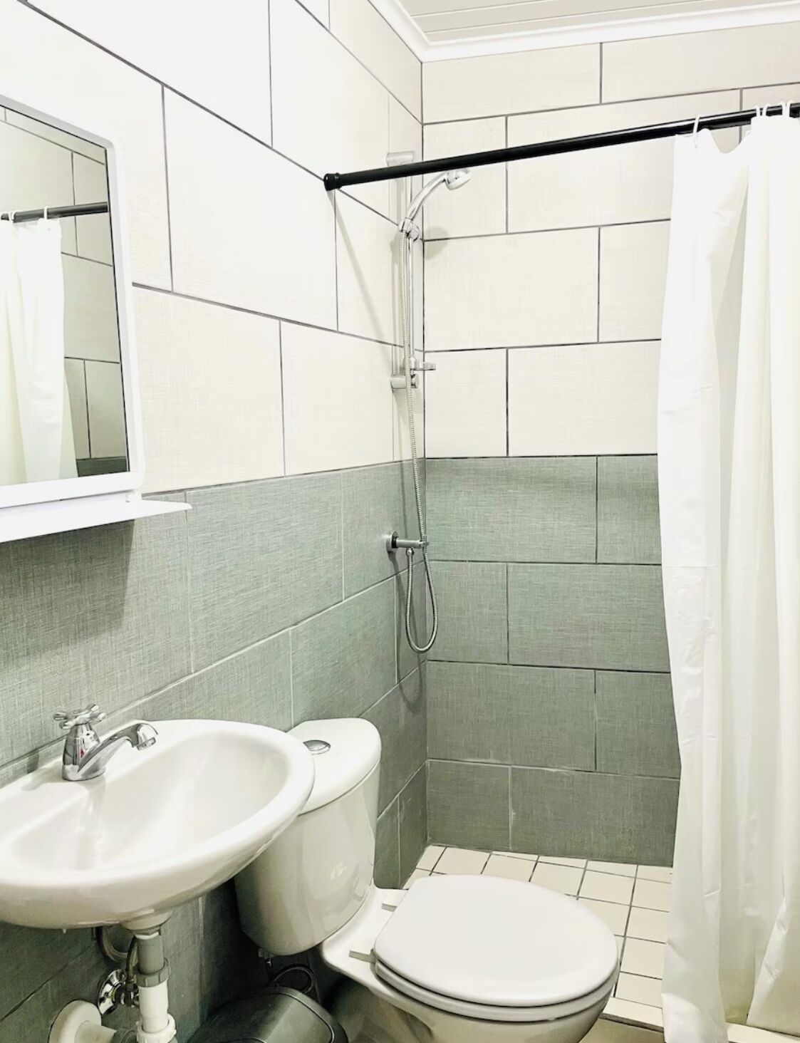 A bathroom with a white sink, toilet, and shower area.