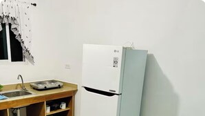 Una cocina compacta con un refrigerador blanco LG, un lavamanos y una pequeña encimera.