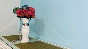 Una mesa blanca con un jarrón de flores y un cuadro en la pared.