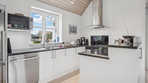 A modern kitchen with white cabinets, a stainless steel dishwasher, a large window, and a view of the outdoors. - Awesome home in Hirtshals with sauna (Hirtshals)