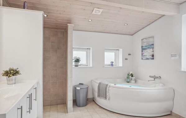 Un baño moderno con una bañera independiente, un tocador con espejo y una planta en maceta.