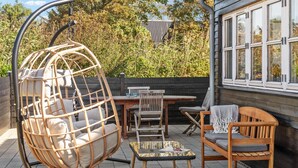 A patio with a hanging chair, wooden table, chairs, and a sofa. - Awesome home in Hirtshals with sauna (Hirtshals)