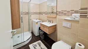 A modern bathroom with a glass shower enclosure, a sink with a mirror, and a toilet. - Mirvana Apartments Allure Studio (Timisoara)