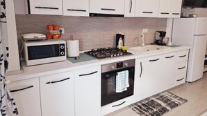 A modern kitchen with white cabinets, a microwave, a gas stove, and a built-in oven. - Mirvana Apartments Allure Studio (Timisoara)