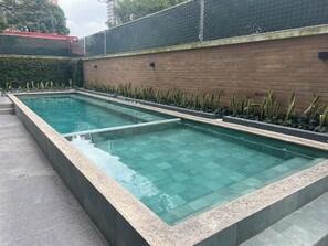 A rectangular swimming pool with clear water, surrounded by a low brick wall and a metal fence. - Entire apartment in zone 10! (Ciudad de Guatemala)