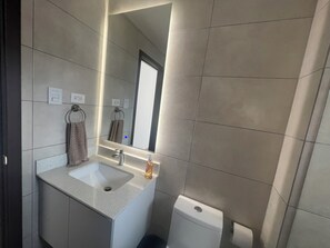 A modern bathroom with a large mirror, a sink, and a toilet. - Entire apartment in zone 10! (Ciudad de Guatemala)