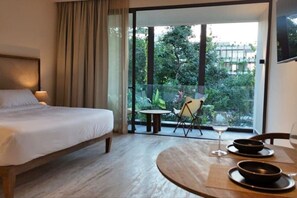 Relax in this stylish room with a large bed, a small table and chair, and a balcony with outdoor seating.