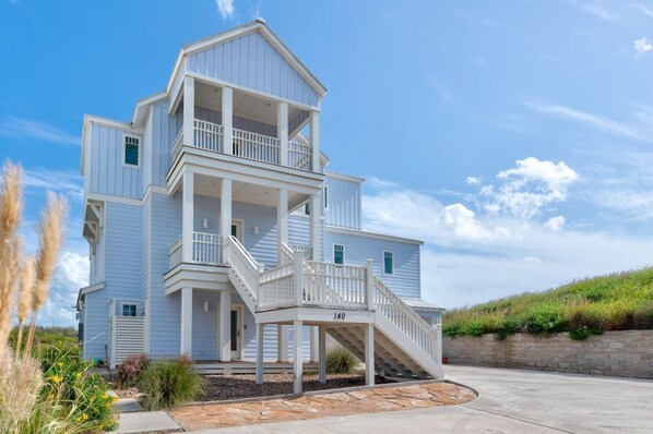 Une maison à plusieurs étages dotée d’un balcon et d’un escalier menant à l’entrée.