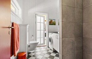 A compact bathroom with a toilet, washing machine, and a sink.