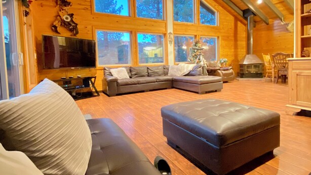 A spacious living room with a large L-shaped sectional sofa, a fireplace, and a high ceiling with exposed beams. - Close to Lake, High Ceilings, Huge Balcony. 2200SF

 (Big Bear Lake)