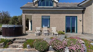 A two-story house with a stone facade, a hot tub, and outdoor seating.