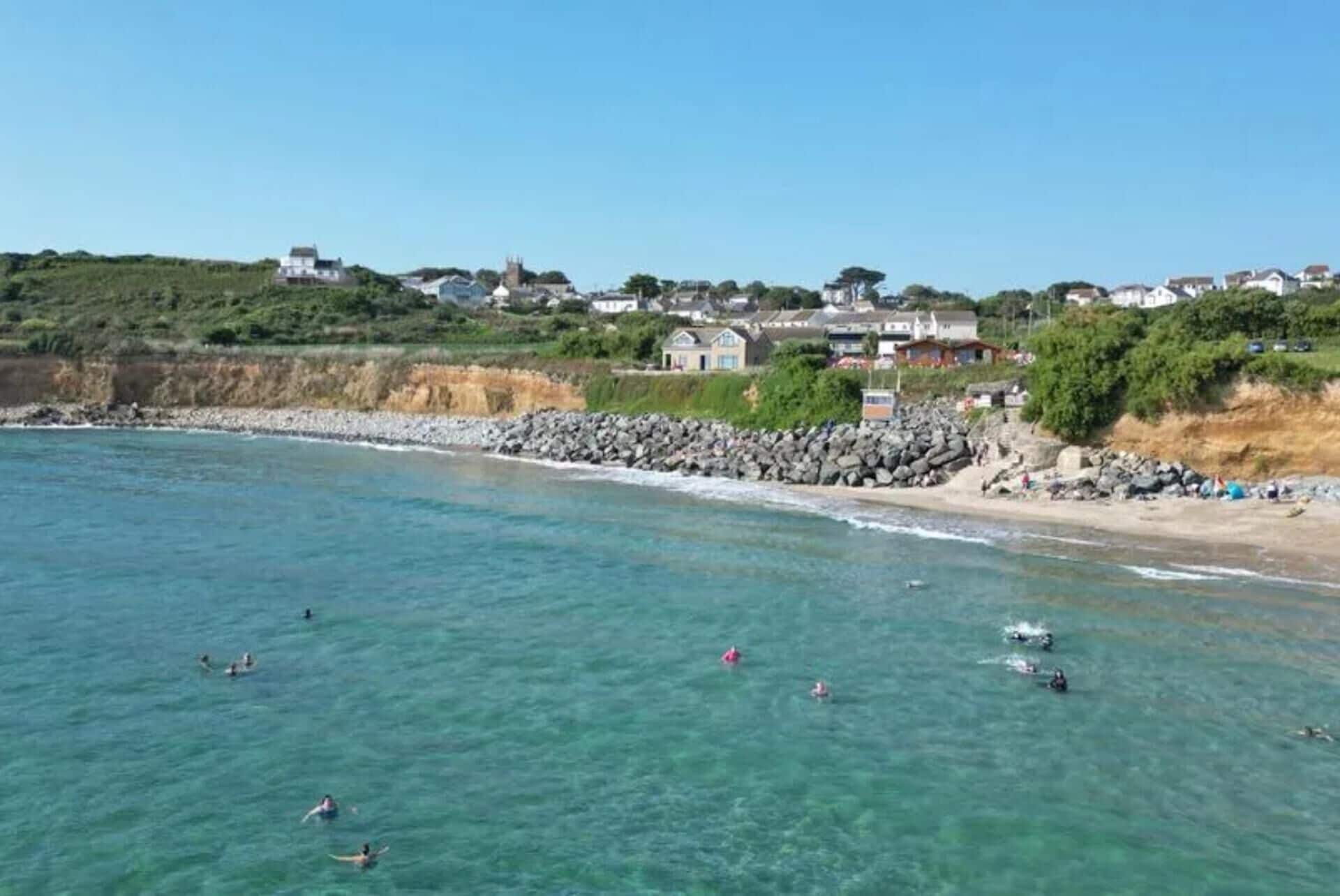 Un pueblo costero con aguas transparentes, una costa rocosa y casas a lo largo de la playa.
