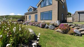 A modern two-story house with large windows, a stone pathway, and a well-maintained lawn.