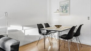 A modern dining area with a white table, black chairs, and a floor lamp. - Nice apartment in Nexø with WiFi (Nexø)