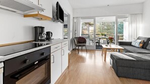 A modern kitchen with a built-in oven and microwave, a dining area with a table and chairs, and a cozy seating area with a sofa. - Nice apartment in Nexø with WiFi (Nexø)