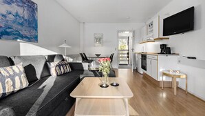 A modern living room with a sofa, a coffee table, and a dining area with a table and chairs. - Nice apartment in Nexø with WiFi (Nexø)