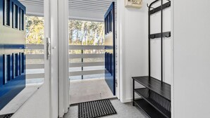 A modern entrance with a metal bench, a wall-mounted rack, and a door leading to an outdoor area with a view of trees. - Nice apartment in Nexø with WiFi (Nexø)