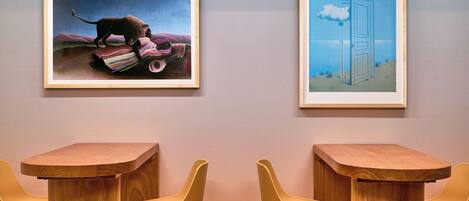 Two framed artworks on a wall, a table, and two chairs.