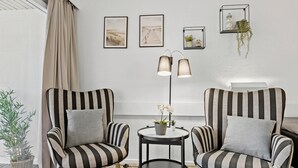 A room with two striped armchairs, a small round table with a plant, and a floor lamp. There are three framed pictures on the wall. - Awesome apartment in Nexø with WiFi (Nexø)