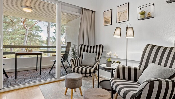 A modern living room with striped armchairs, a round table, and a balcony with a view of trees. - Awesome apartment in Nexø with WiFi (Nexø)