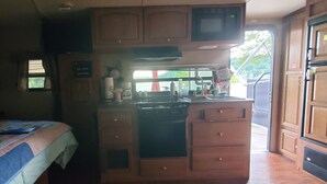 Un intérieur de camping-car compact comprenant un coin cuisine, un lit et une fenêtre donnant sur l’extérieur.