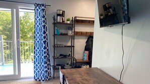 A room with a wooden table, a TV mounted on the wall, and a shelf with kitchen items. - Newly Renovated 2-Bedroom Oasis (Toronto)
