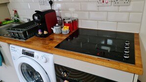 A compact kitchen with a washing machine, a coffee maker, and a microwave. - Stylish studio- 15mins to Central London! (London)