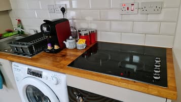 A compact kitchen with a washing machine, a coffee maker, and a microwave.