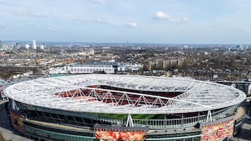 A stadium with a large central field and surrounding seating, surrounded by urban buildings.