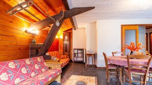 Ein gemütliches Holzinnere mit einer Couch, einem Esstisch und einem Bücherregal.