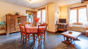 Ein gemütliches Zimmer mit einem Holzesstisch, Stühlen, einem Fernseher und einem Schrank.