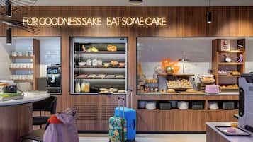 A modern cafe with a wooden interior, a counter with a menu, and a display case with various food items.