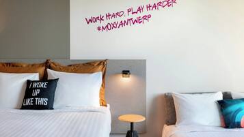 Habitación de hotel con dos camas, una lámpara de pared y una frase motivadora.