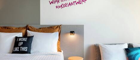 A hotel room with two beds, a wall-mounted light, and a motivational quote.