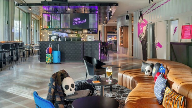 A modern hotel lobby with a bar area, seating arrangements, and a neon sign. - Moxy Antwerp (Antwerp)