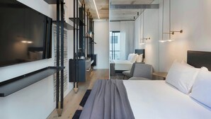 A modern hotel room with a large bed, a desk, a chair, and a TV mounted on the wall. - Gymnasia Isrotel, A Tribute Portfolio Hotel (Tel Aviv)