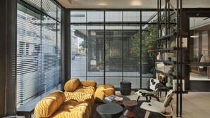 A modern living room with a sofa set, a coffee table, and a bookshelf. - Gymnasia Isrotel, A Tribute Portfolio Hotel (Tel Aviv)