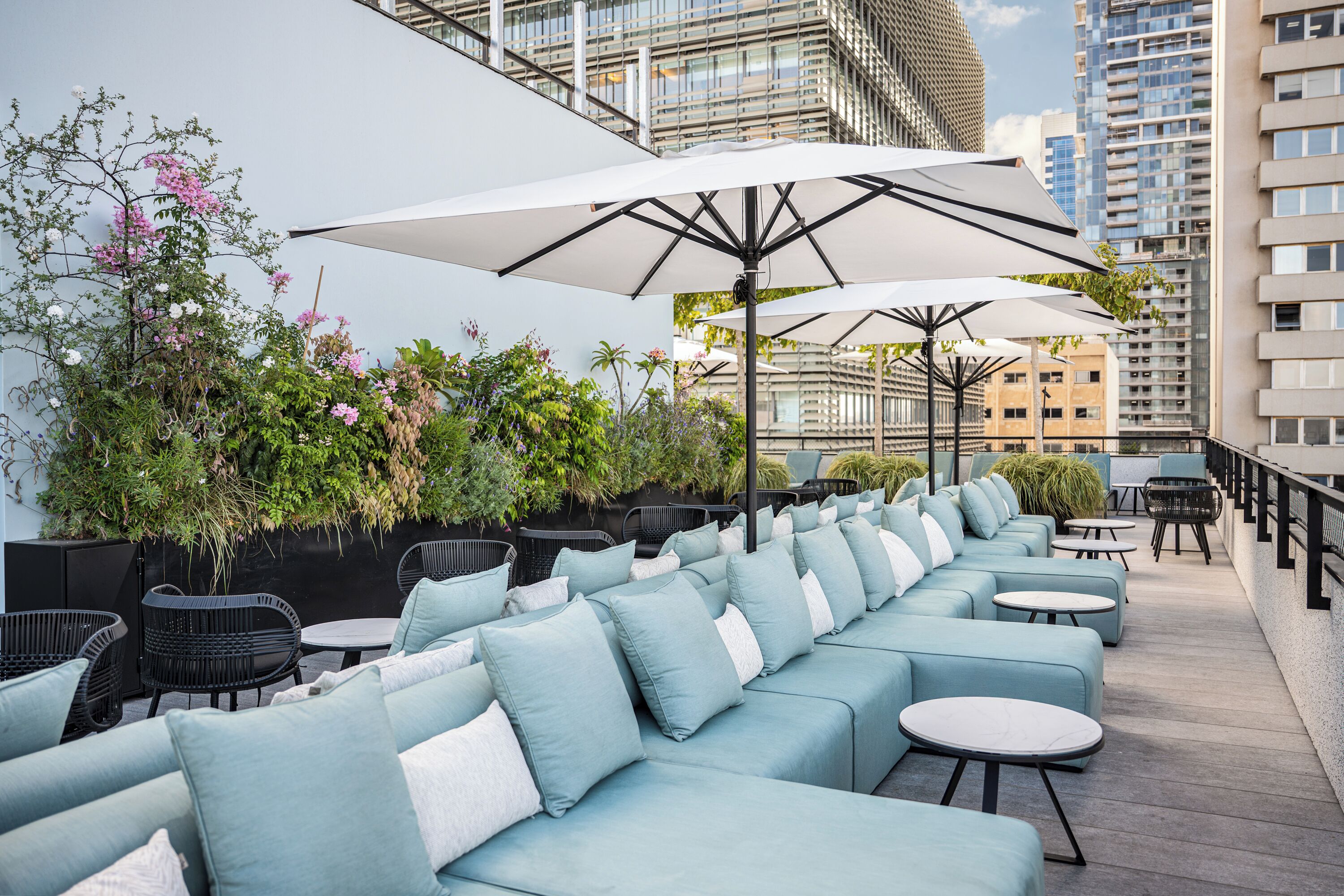 A rooftop terrace with outdoor seating, umbrellas, and a view of surrounding buildings.