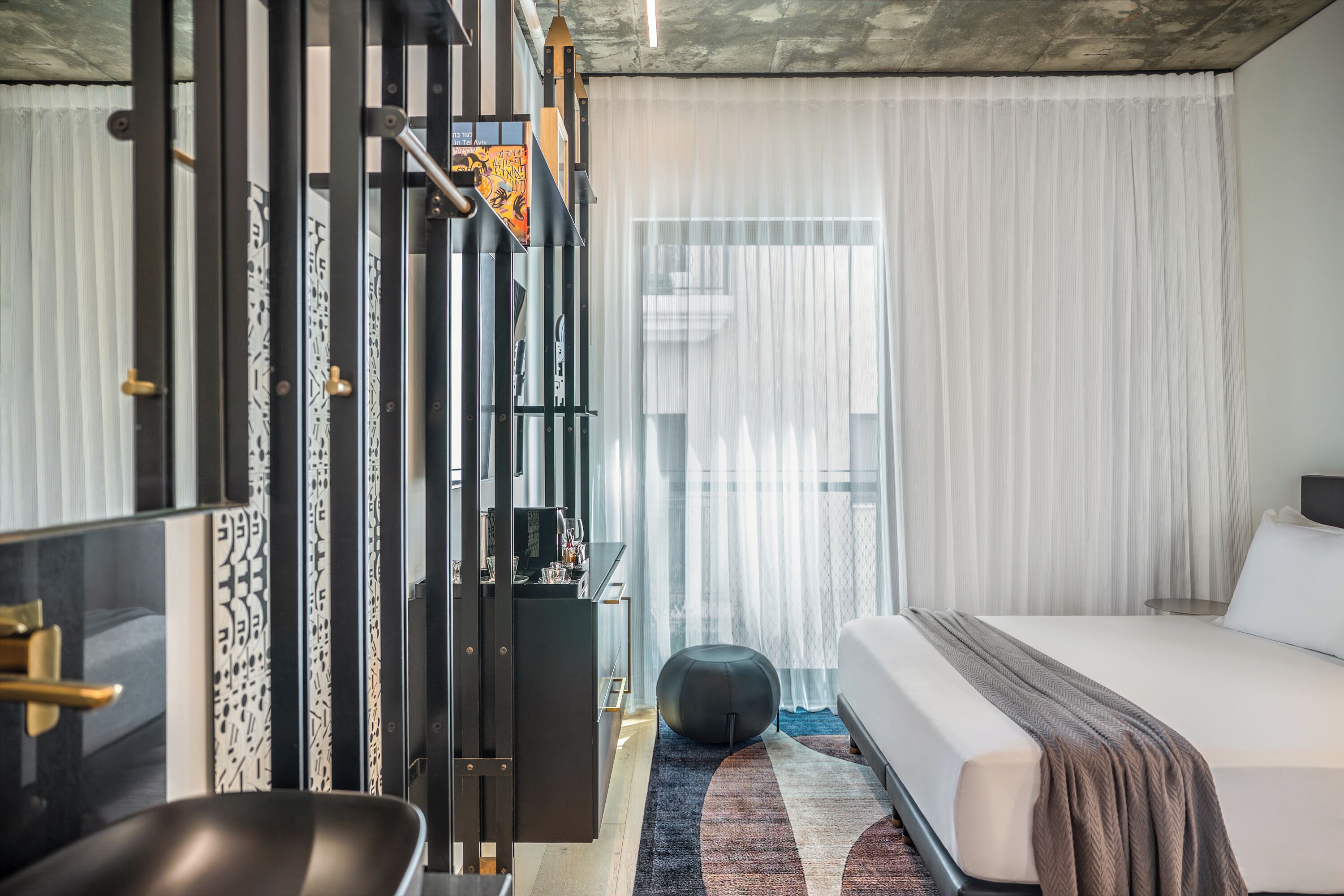 A modern hotel room with a large bed, a desk, and a wardrobe.